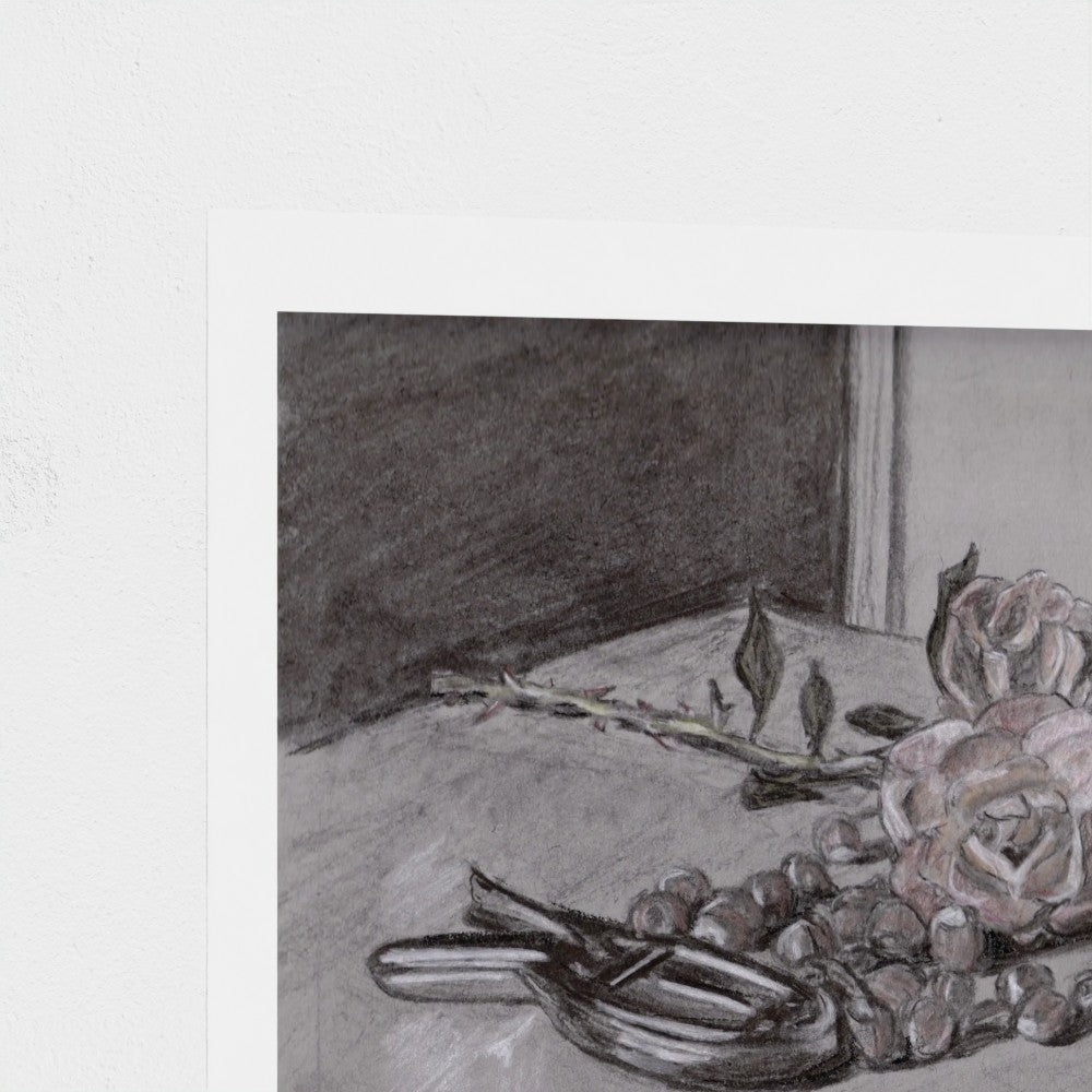 A square art print featuring a charcoal and pencil still life sketch of roses, nuts, and a stem on a table, shown with a white border against a textured off-white background.