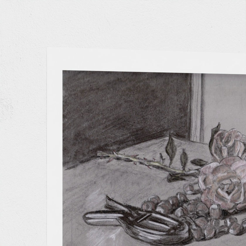 A square art print featuring a charcoal and pencil still life sketch of roses, nuts, and a stem on a table, shown with a white border against a textured off-white background.