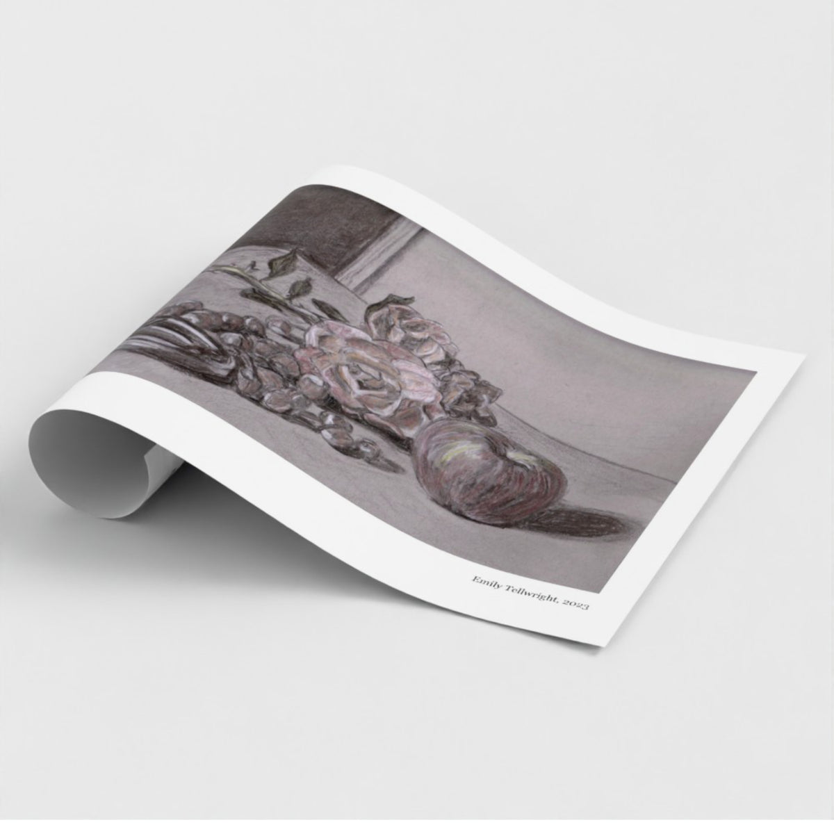 A rolled-out art print showing a monochrome sketch of flowers and fruit, photographed on a clean light gray background. The print has a white border and small printed text along the right edge.