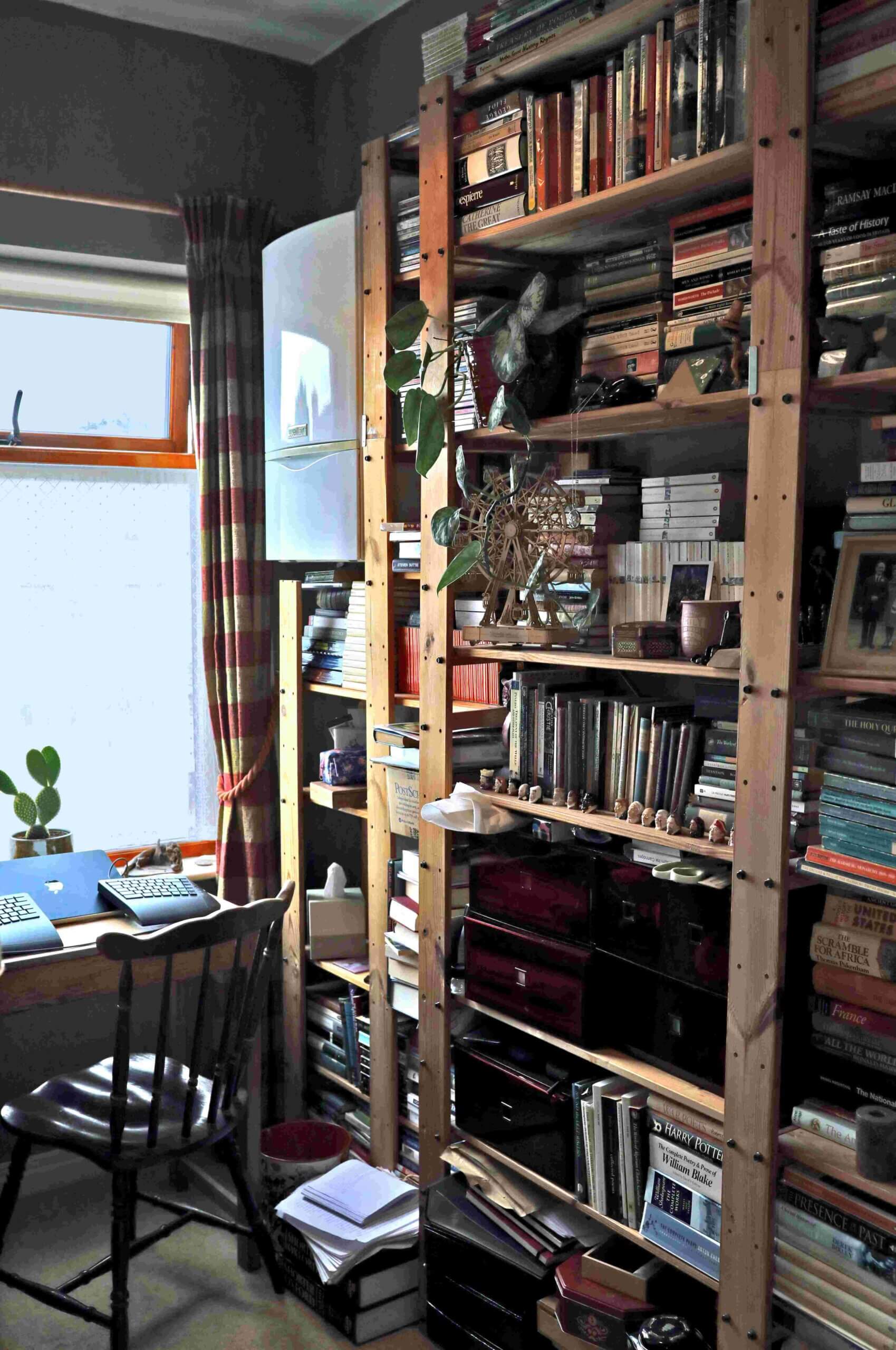A photo of a small study with a window, desk with mac laptop and bookshelves that is Castle Sefton Press headquarters and tells you a bit about us