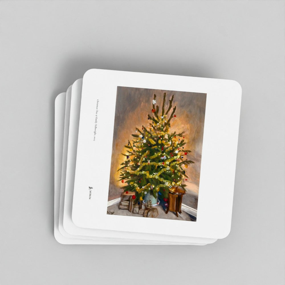 A stack of square white coasters with rounded corners, featuring a printed illustration of a decorated Christmas tree on the top card, photographed on a light grey background.