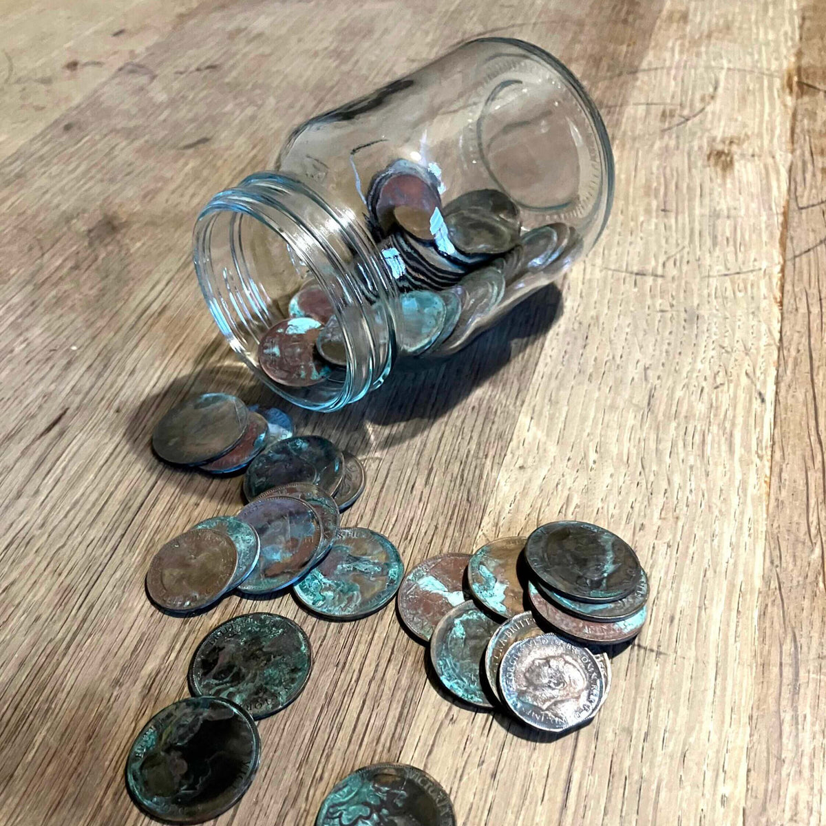 Donations for readers of second hand copies: Glass jar on its side on a table with old coins spilling out.