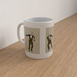 A white ceramic mug with two vertical panels featuring vintage black-and-white illustrations of a man in a tuxedo, placed on a light wood tabletop against a plain wall.