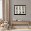 A framed wall art print featuring six vintage black-and-white illustrations of dancers, displayed in a modern living room setting above a light wood console table.