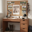 A warm wood desk in a home office setting, decorated with equestrian-themed photos on a cork board, a black riding helmet, books, and tall brown leather riding boots underneath.