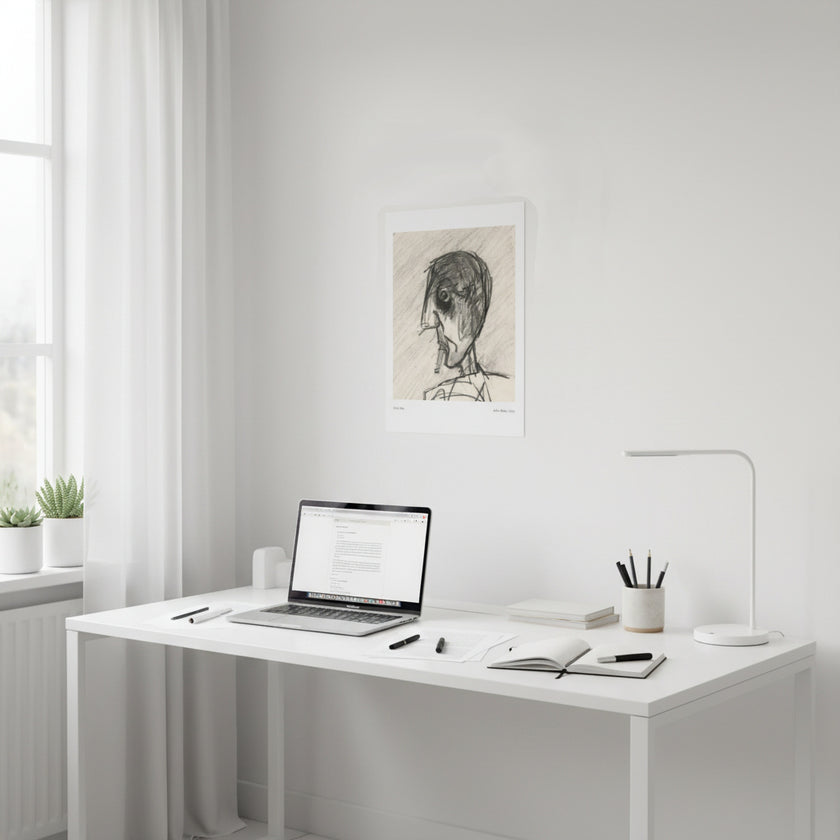 an art print of a drawing of a smoking person above a white desk with a laptop on