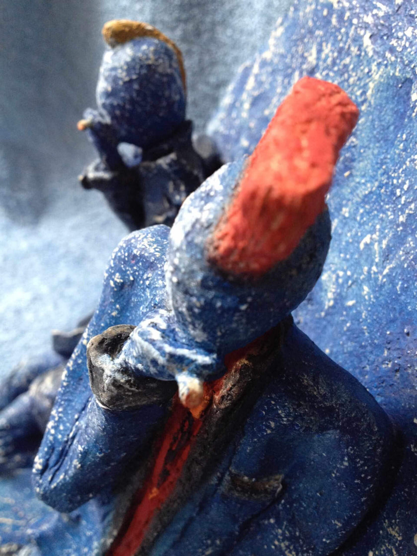 Ceramic sculpture of two punks leaning on a wall smoking.