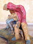 Ceramic sculpture of two figures sitting in hoodies looking at mobile phones with a dog at their feet.