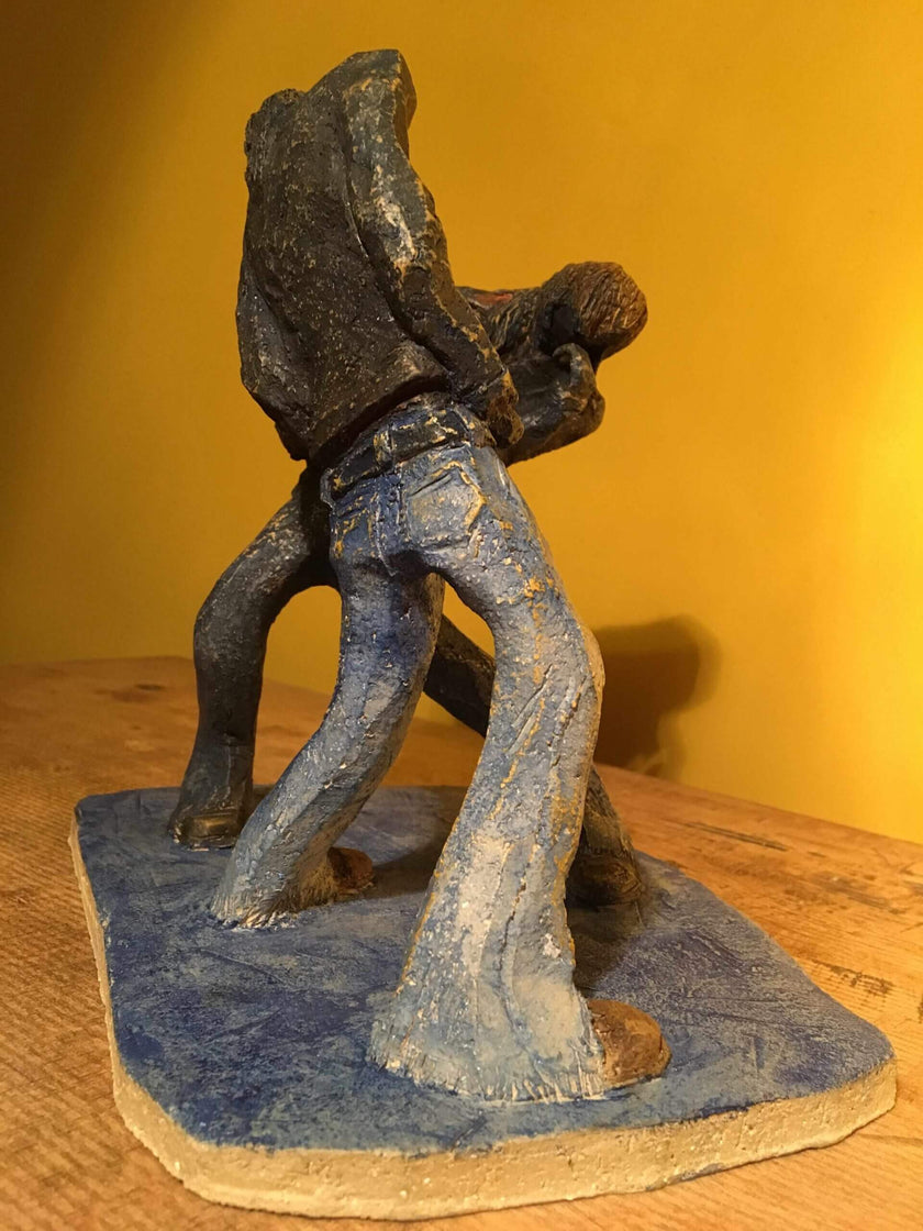 Ceramic sculpture of two air guitarists duelling.