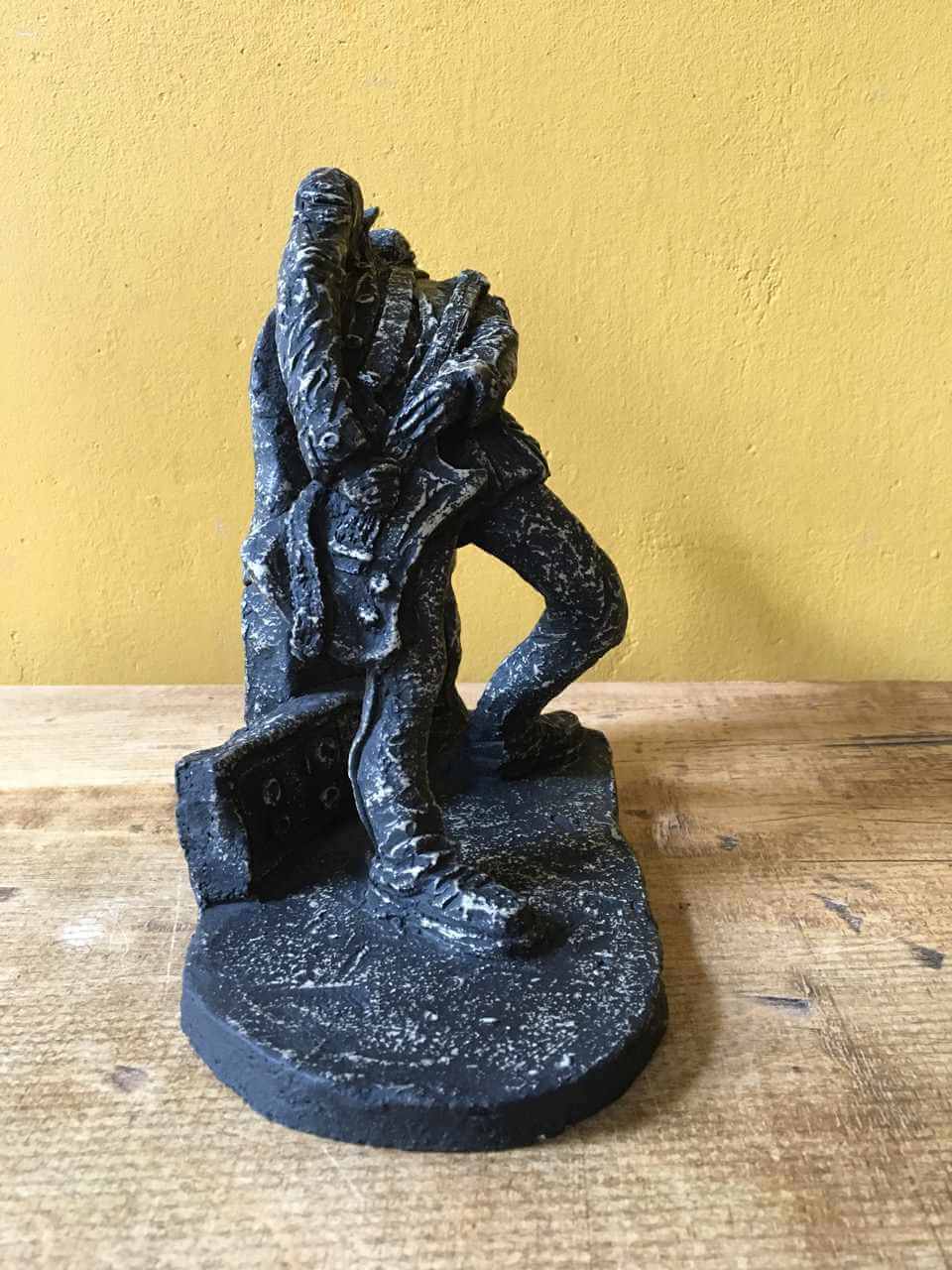 Ceramic sculpture of a rock guitarist painted black.
