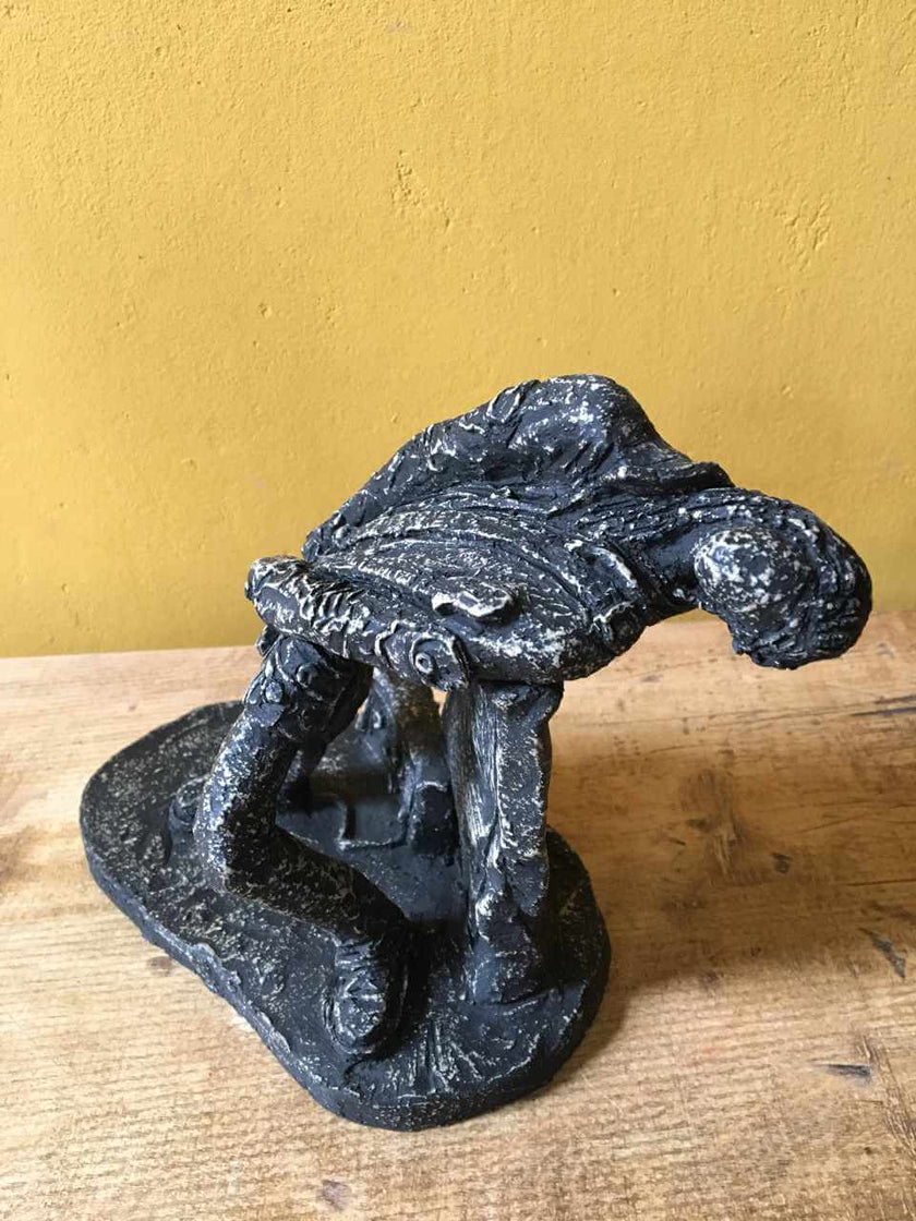 Ceramic sculpture of a rock guitarist painted black.