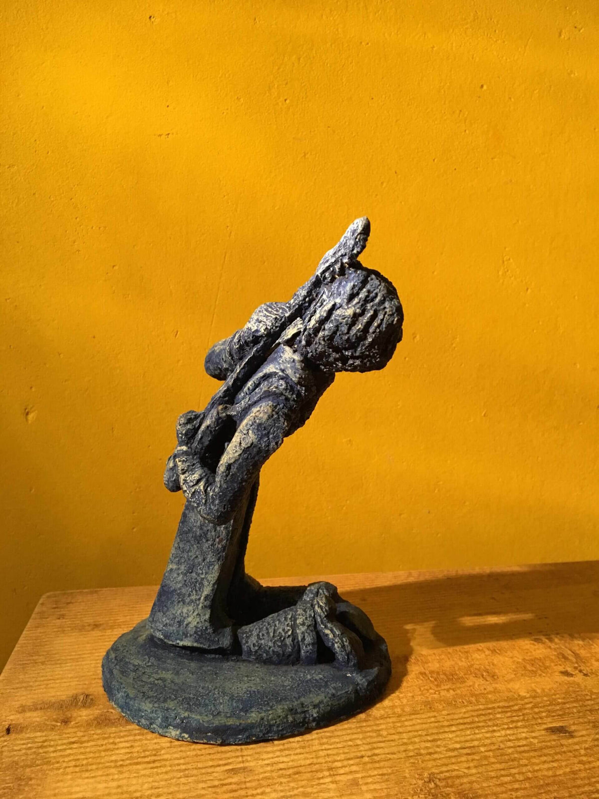 Ceramic sculpture of a kneeling guitarist painted blue.