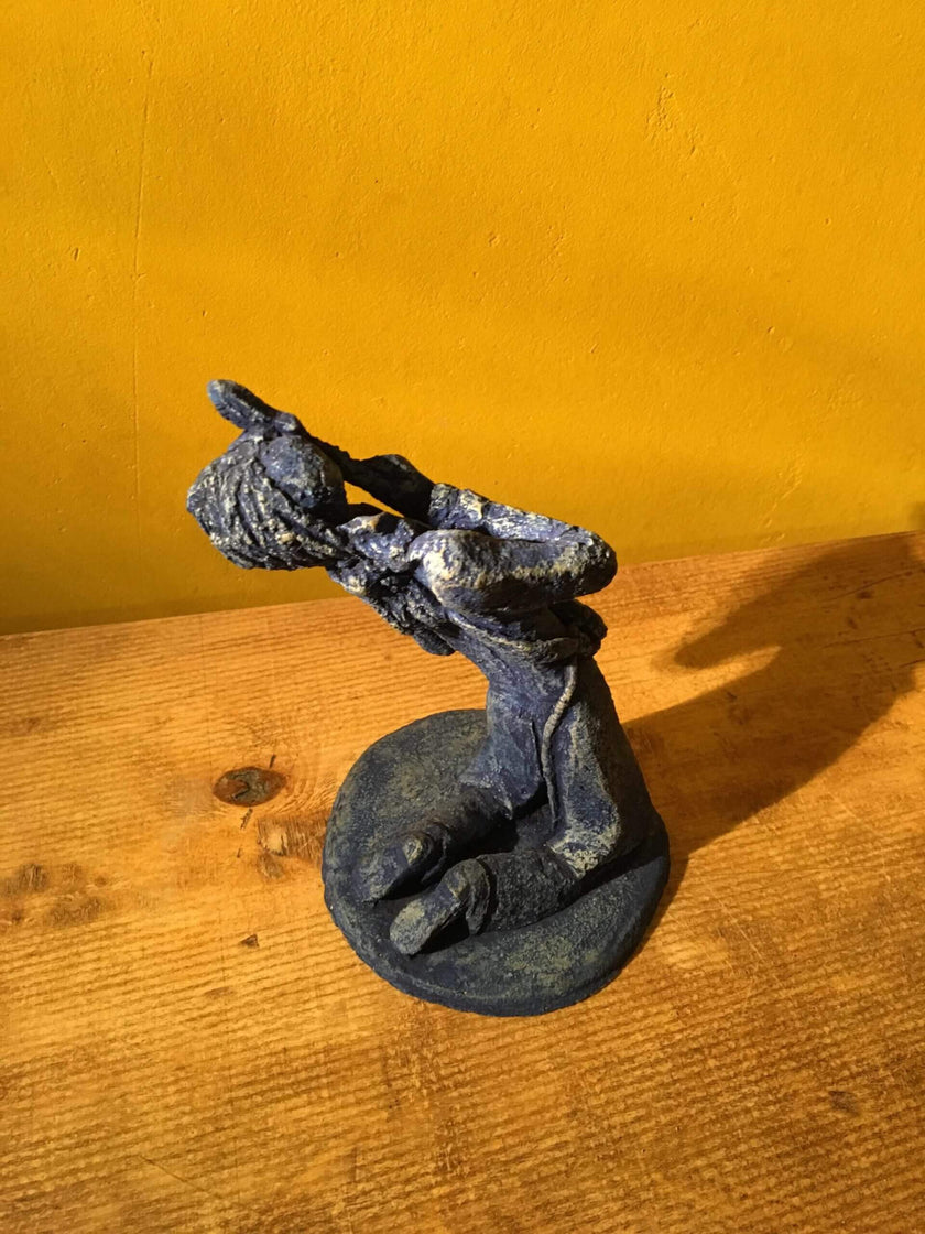 Ceramic sculpture of a kneeling guitarist painted blue.
