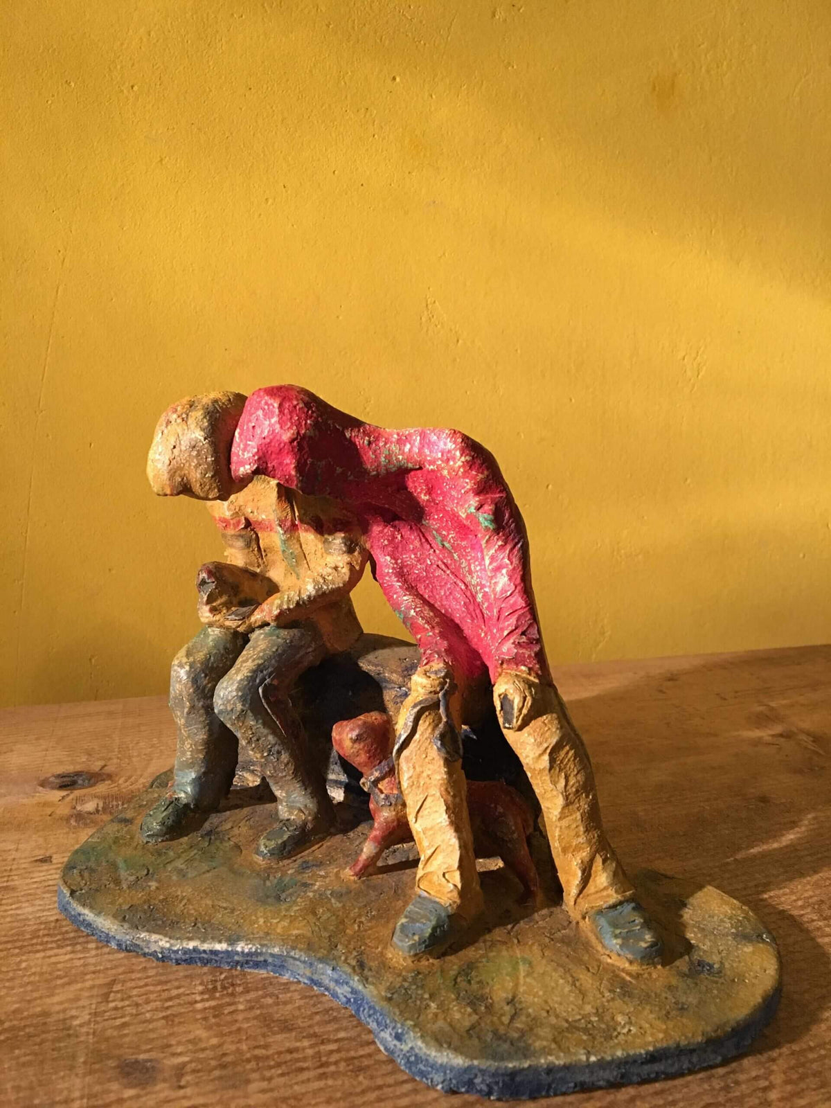 Ceramic sculpture of two figures sitting in hoodies looking at mobile phones with a dog at their feet.