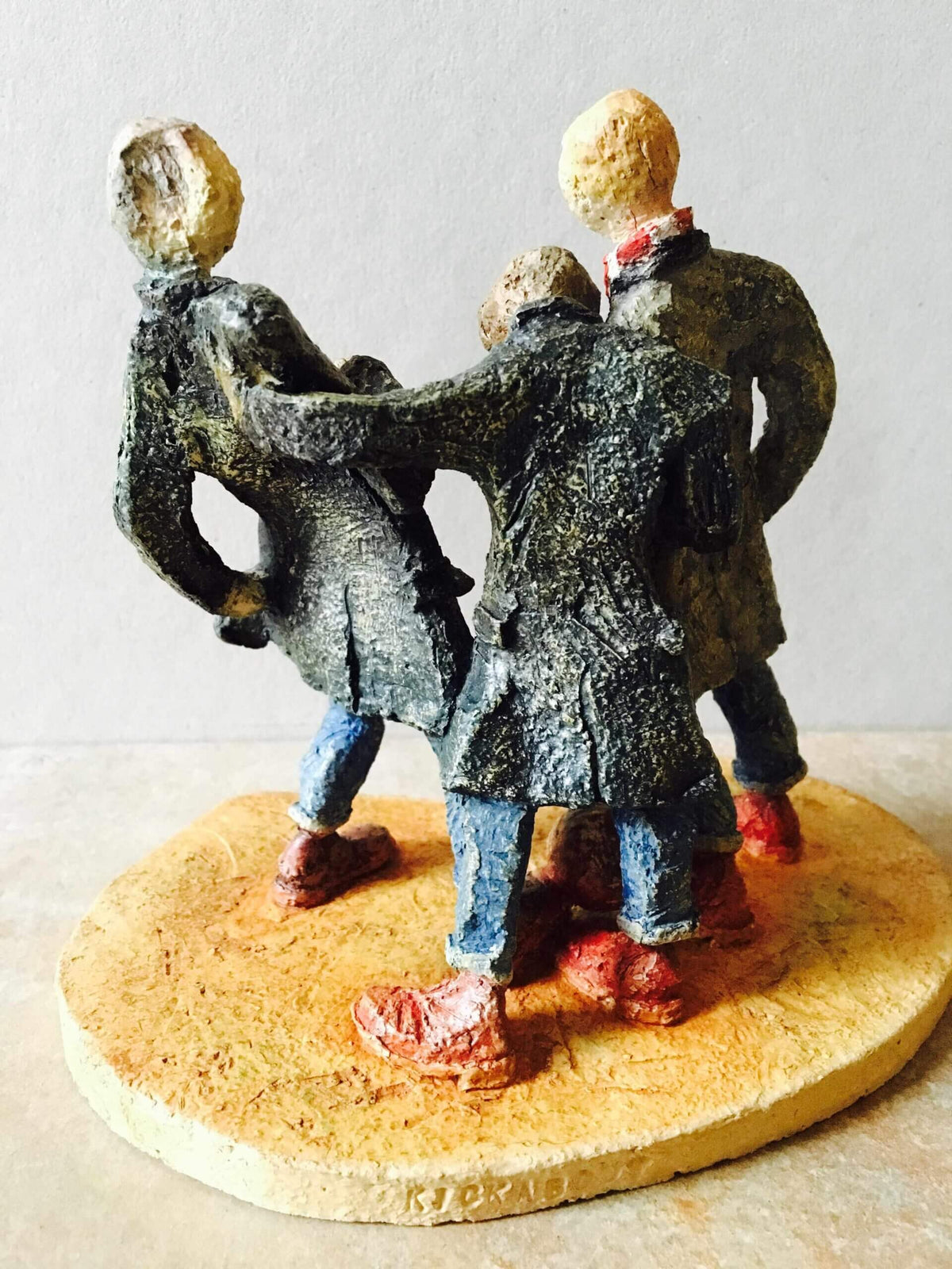 ceramic sculpture of figures in coats kicking a football around