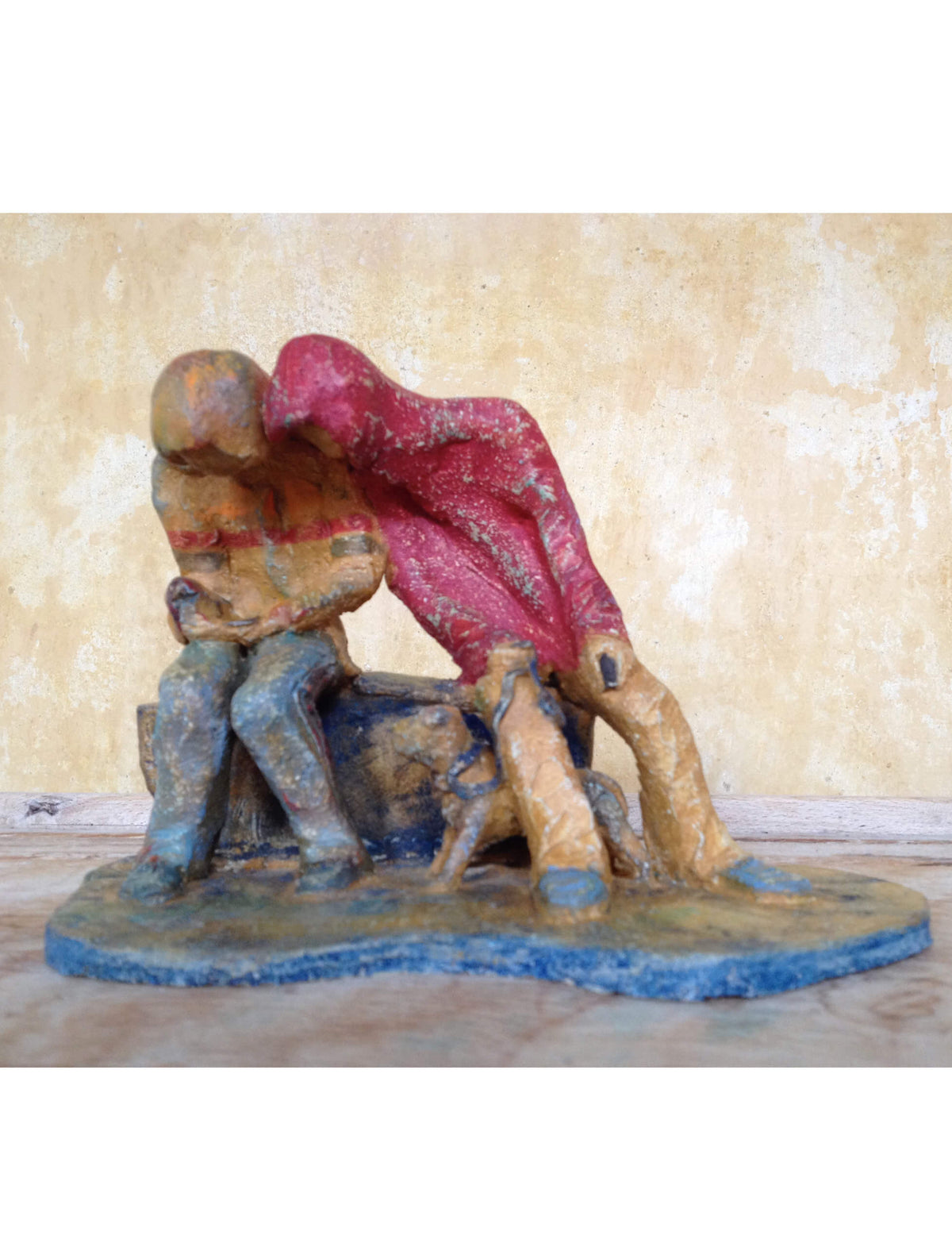 eramic sculpture of two figures sitting in hoodies looking at mobile phones with a dog at their feet.