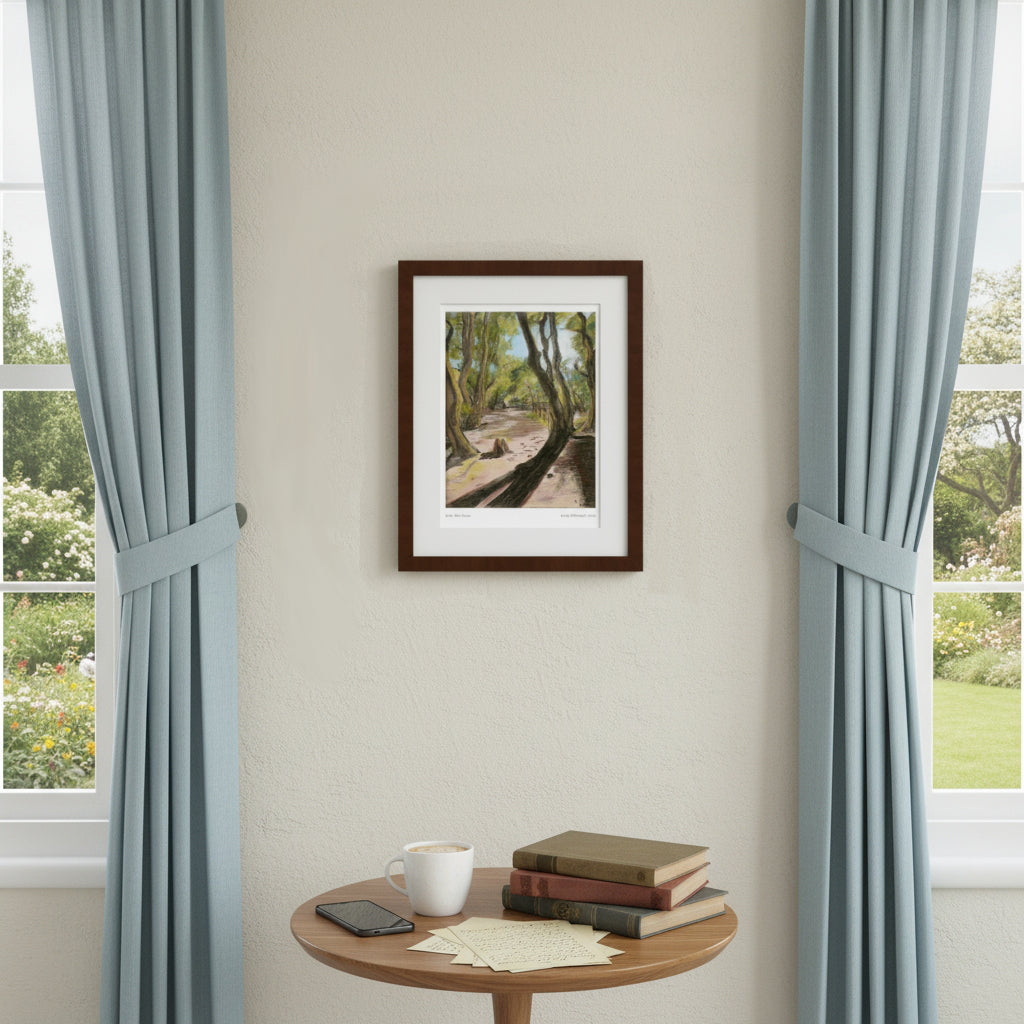 A framed art print depicting a sunlit forest path hangs on a beige wall between two light blue curtains. A small round wooden table below holds a mug, papers, and stacked books.
