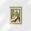 A greeting card featuring a painted forest path scene, presented in a clear sleeve with a kraft envelope behind it on a white background.