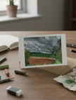 Summer Storm Near Witley Court Greetings Card on a table with artists pastels