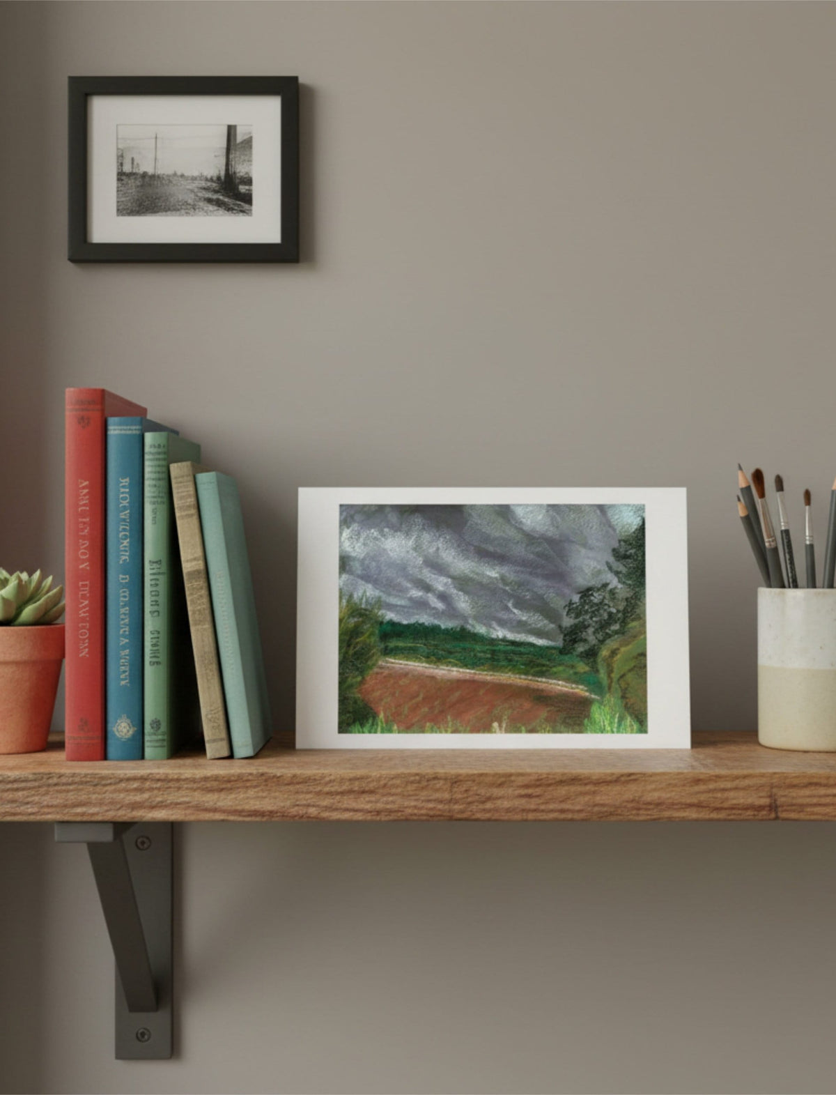 Summer Storm Near Witley Court Greetings Card on a shelf with books and a plant
