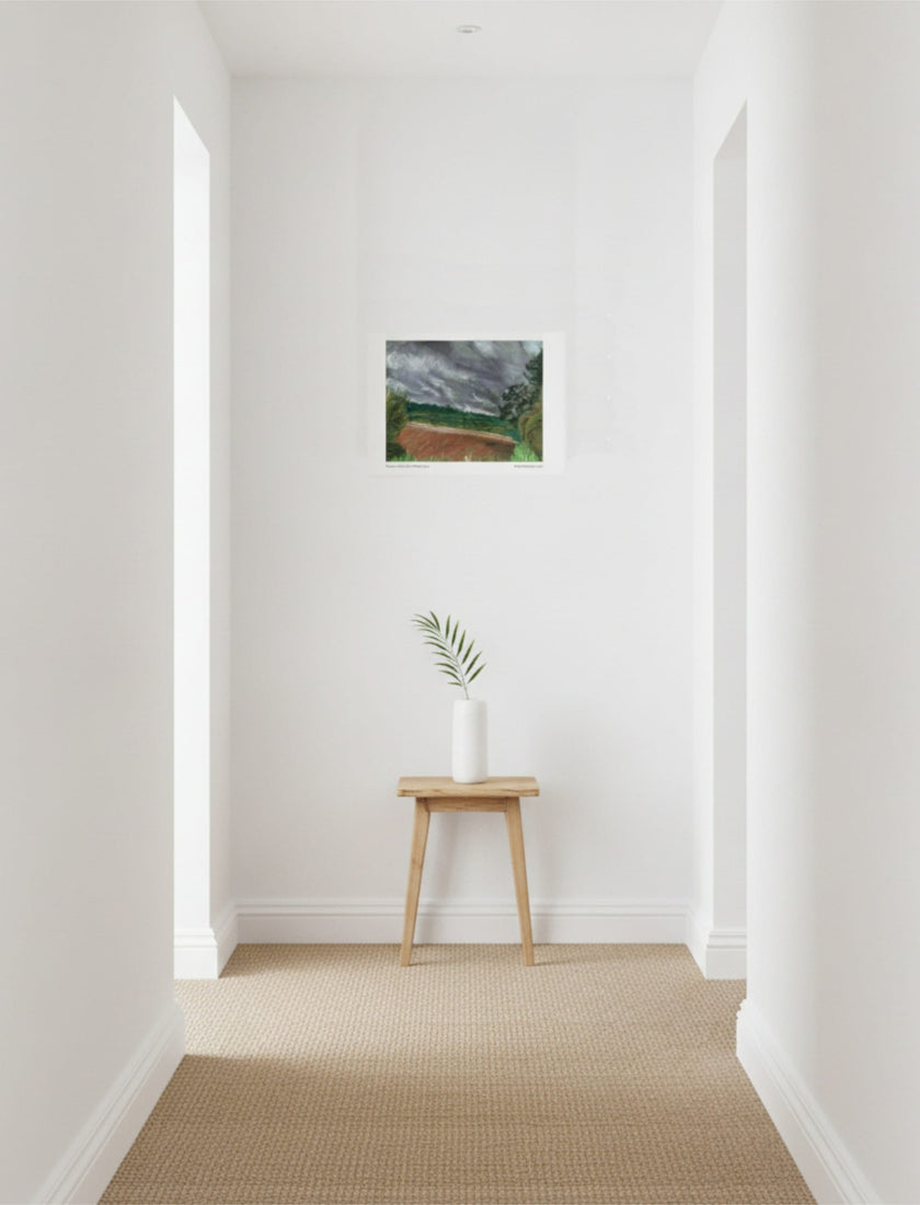 Summer Storm Near Witley Court Art print on wall above a table with a plant on
