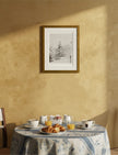 Snowy Fir Tree Framed Art Print hanging on a yellow wall above a breakfast table