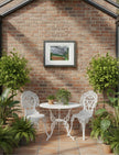 Summer Storm Near Witley Court Framed Art Print on a brick wall above white iron garden furniture with plants
