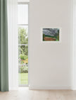 Summer Storm Near Witley Court Art print on wall next to a window with green curtains