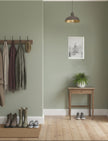 Snowy Fir Tree Art Print A4 on a green wall above a side table in a hall with shoe and coats