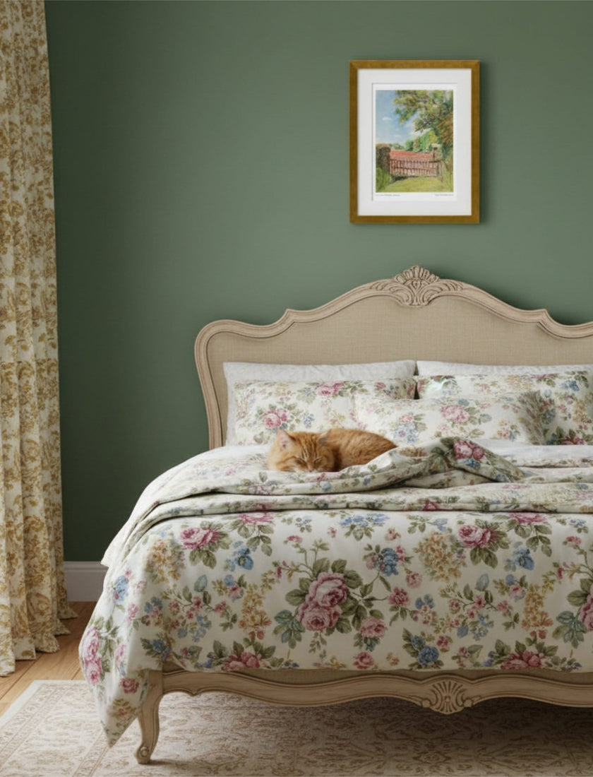 the view from St Mary's Kempley Framed Art Print above a bed with chintz covers and a cat