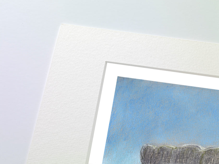 Close-up of a matted art print corner, showing textured white paper matting around a blue-toned painting or print with a dark grey textured form at the bottom.