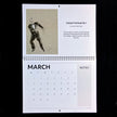 A spiral-bound calendar page from March featuring a black-and-white sketch of a man in a tuxedo with the title 'Fantastic Fred Astaire No 2' and a printed notes section, photographed against a black background.