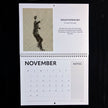 A spiral-bound November calendar page laid flat against a black background. The top section features an art print titled 'Fantastic Fred Actaire No 6' with a monochrome figure drawing and descriptive text.