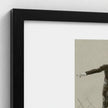 A close-up of a framed wall art print with a thick black frame and white mat, showing part of a monochrome figure artwork on a beige background.