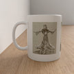 A white ceramic mug with a printed sepia-toned sketch of a woman in a flowing dress, shown sitting on a light wood tabletop against a neutral wall.