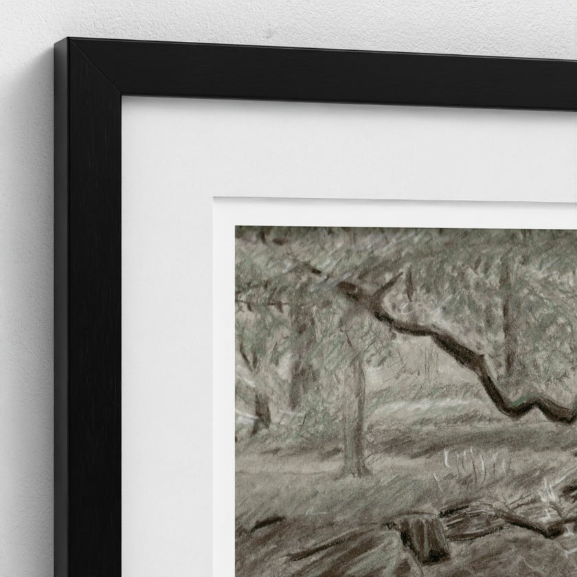 A close-up of a framed art print with a black frame and white mat, showing a monochrome still life drawing of fruit on a table.
