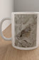 A white ceramic mug with a printed illustration of a small brown bird on a textured gray background, sitting on a light wood tabletop against a neutral wall.