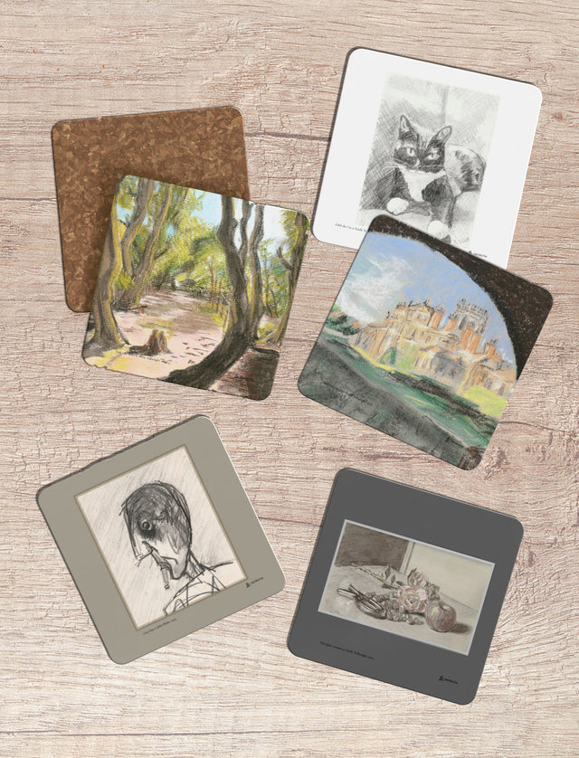 Five square art coasters with mixed media sketches and paintings are arranged on a light wood background. The prints feature various subjects including a cat, a forest scene, a castle, a bird, and a portrait, each with different frame colors and one print showing a cork backing.