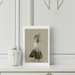 A greetings card showing ginger rogers, displayed on a white shelf next to a white ceramic vase with gold accents.