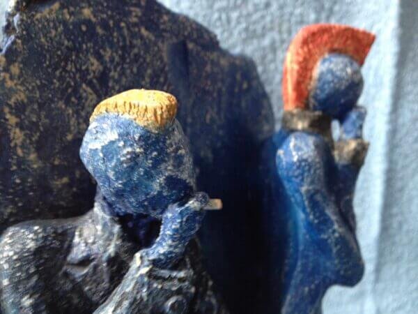 Ceramic sculpture of two punks leaning on a wall smoking.