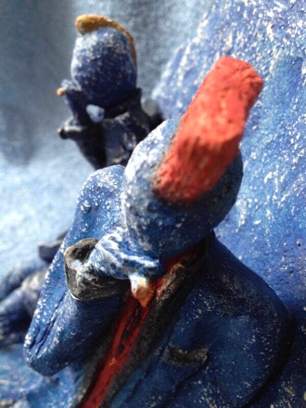 Ceramic sculpture of two punks leaning on a wall smoking.