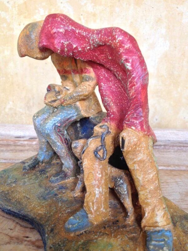 Ceramic sculpture of two figures sitting in hoodies looking at mobile phones with a dog at their feet.
