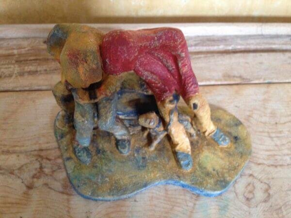 Ceramic sculpture of two figures sitting in hoodies looking at mobile phones with a dog at their feet.