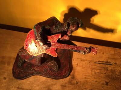 Ceramic sculpture of a rockabilly guitarist painted red.