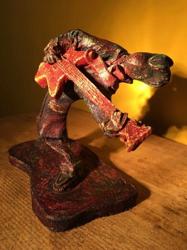 Ceramic sculpture of a rockabilly guitarist painted red.