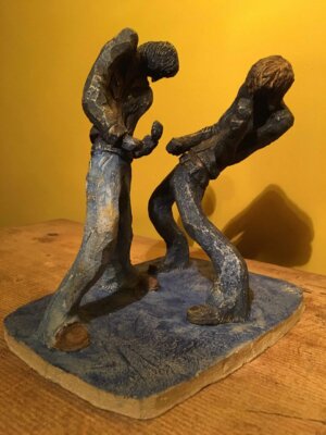 Ceramic sculpture of two air guitarists duelling.