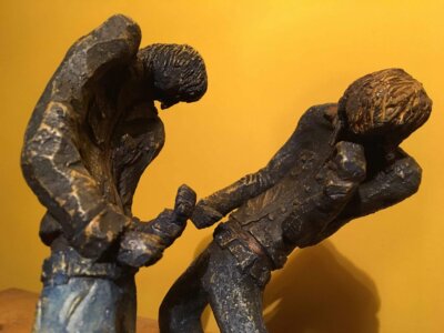 Ceramic sculpture of two air guitarists duelling.