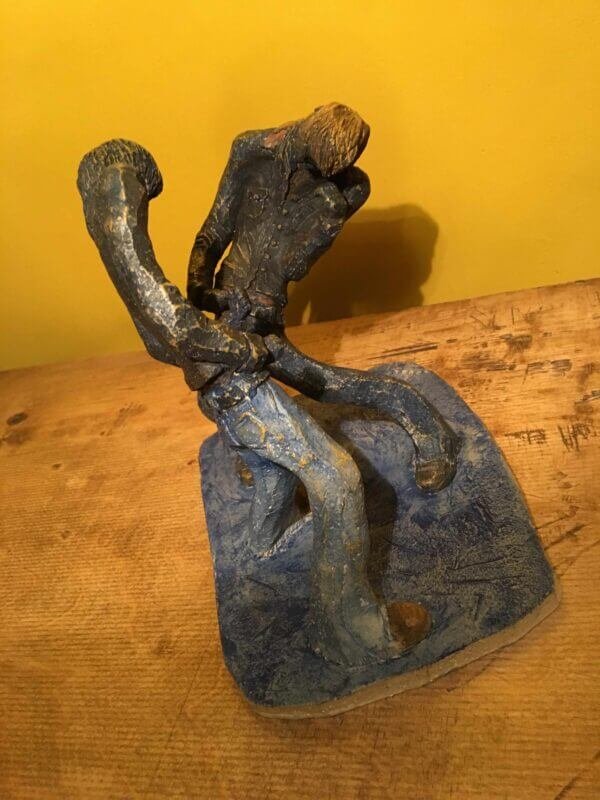 Ceramic sculpture of two air guitarists duelling.