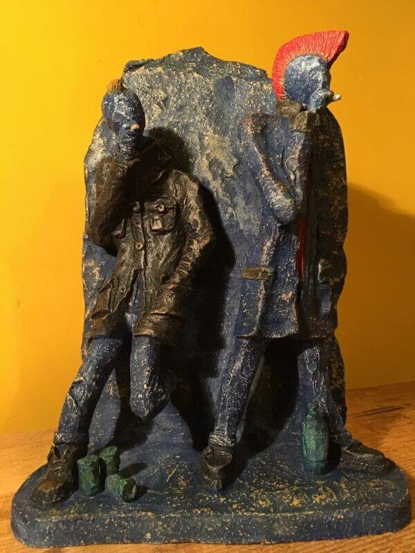 Ceramic sculpture of two punks leaning on a wall smoking.