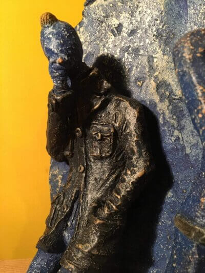 Ceramic sculpture of two punks leaning on a wall smoking.